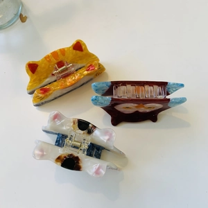 Detailed view of acetate hair claws in cat and owl shapes with glossy finish