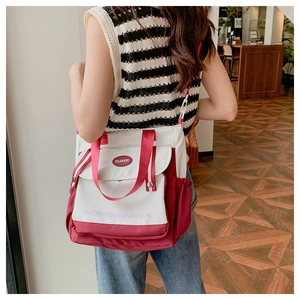 Detail of burgundy and white canvas tote bag showing side pocket and adjustable strap