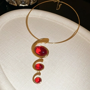 Detailed view of red oval resin pendant necklace on a cream textured jewelry tray