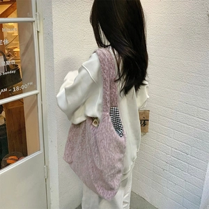 Detailed view of the soft pink plush tote bag with a checkered lining on a model