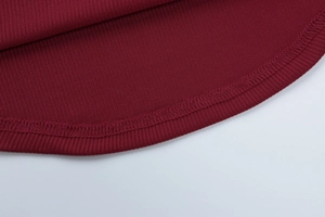 Dettaglio del tessuto a costine rosso scuro con cuciture di qualità e un orlo curvo unico