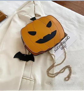 Detail of pumpkin crossbody bag with gold chain and bat charm on a beige blazer