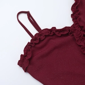 Dettaglio dell'abito bordeaux glitterato con scollo a balze e spalline sottili