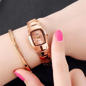 Close-up of a tonneau-shaped rose gold quartz watch with a matching metal bracelet