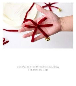 Detail of red velvet Christmas bow with a small golden bell held in hand