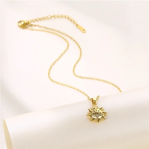 Golden sun totem pendant necklace with zircon stones on white silk background