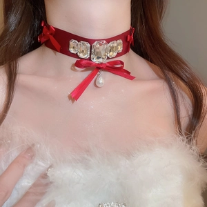 Close-up of burgundy velvet choker with crystal inlay, bow, and teardrop pearl pendant