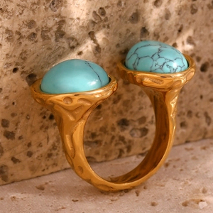 Detail of gold open ring with turquoise stones on natural beige stone texture