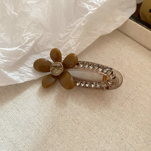 Detail of floral hair clip with amber petals, sparkling rhinestones and golden accents
