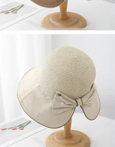 Dettaglio di un cappello di paglia beige con tesa larga ed elegante fiocco laterale