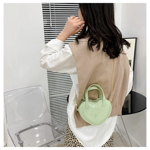 Rear view of model wearing a mint green heart-shaped jelly bag with gold chain strap
