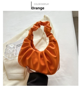 Detail of an orange ruched underarm bag with vintage French design and pleated handle