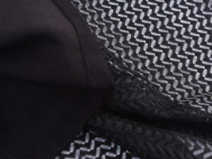 Close-up of elegant black mesh fabric showing fine hollow weave and ruffle texture