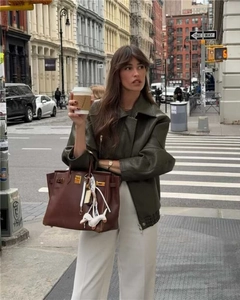 Dettaglio della giacca vintage in similpelle oliva con borsa a mano marrone di design