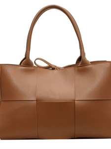 Brown woven leather tote bag with dual handles and tie detail on white background