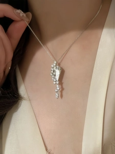Close-up of hourglass pendant necklace with shimmering crystals on minimalist silver chain