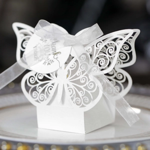 Close-up of laser-cut butterfly wedding favor box with white ribbon and thank you tag