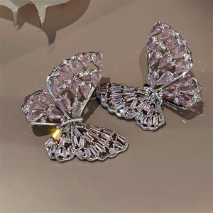 Macro view of butterfly earrings with pink and purple zircons on a silver setting