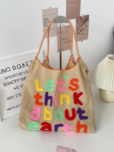 Detail of colorful embroidered text Let's think about earth on a khaki canvas tote bag