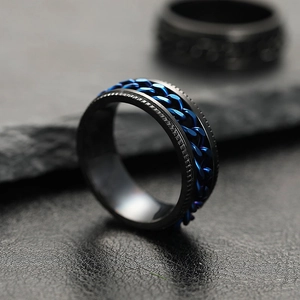 Macro detail of men's stainless steel ring with black frame and blue rotating chain