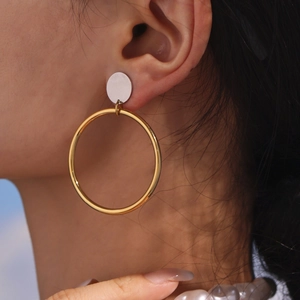 Boucles d'oreilles créoles en acier doré 18 carats avec clou argenté portées par modèle