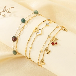 Dettaglio di cinque braccialetti dorati con ciondoli a ciliegia e cuori pendenti