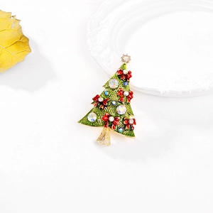Close-up of Christmas tree brooch with green enamel, red bows and shiny rhinestones