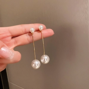 Gros plan de boucles d'oreilles doubles perles avec longue chaîne à franges dorée