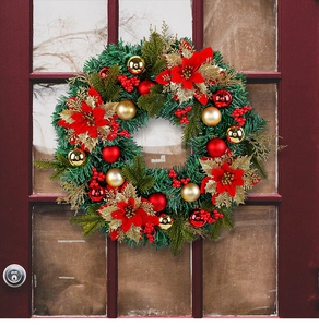 Detail of a Christmas wreath with red poinsettias, gold baubles, and berries on a wooden door