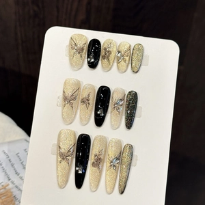 Detailed view of handmade press-on nails with rose and butterfly motifs and rhinestones