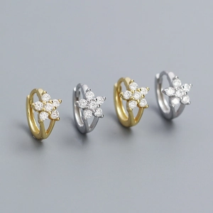 Close-up of gold and silver S925 earrings with sparkling floral cubic zirconia charms