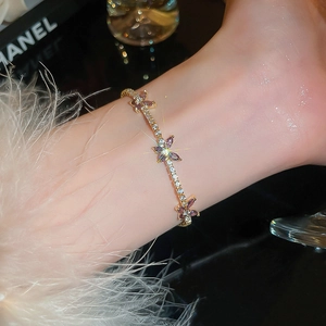 Dettaglio macro del raffinato bracciale a farfalla dorato con zirconi viola sul polso