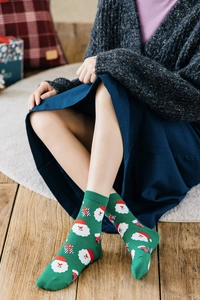 Detail von grünen Weihnachts-Baumwollsocken mit Weihnachtsmann-Muster in gemütlichem Heim