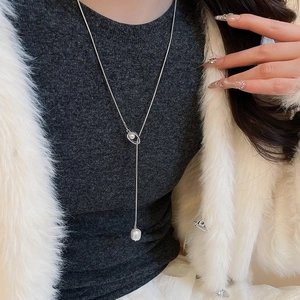 Detailed view of an elegant silver Y-shaped pearl necklace on a female model