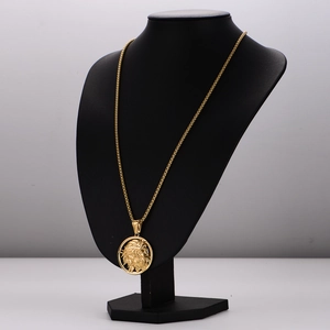 Vintage gold stainless steel necklace with relief pendant on black velvet display