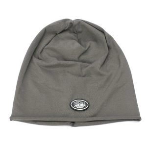 Detail of dark grey knit beanie featuring a black rubber logo patch and rolled edge