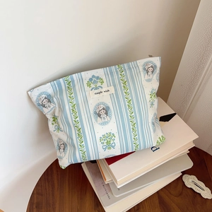 Detailed close-up of a floral cotton makeup bag with vintage girl print on a blue striped fabric