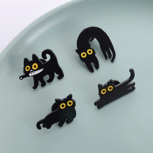 Set of four punk black cat enamel pins with daggers and yellow eyes on a dish