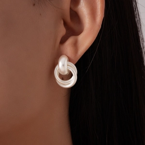 Gros plan de boucles d'oreilles nœuds géométriques en argent mat avec trois anneaux entrelacés