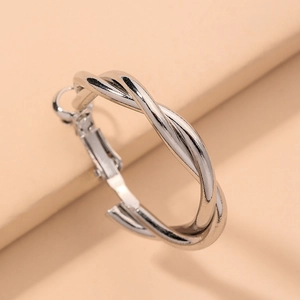 Macro detail of twisted silver hoop earrings with a polished geometric spiral texture
