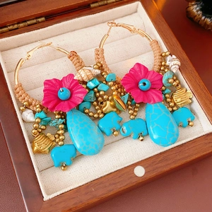 Detail of bohemian hoop earrings with pink flowers and turquoise beads in a wooden box