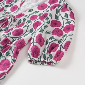 Détail de la blouse florale avec manches bouffantes, poignets élastiques et liens noués