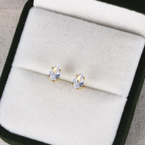 Macro shot of 6-12mm gold pear-cut cubic zirconia earrings on green velvet box