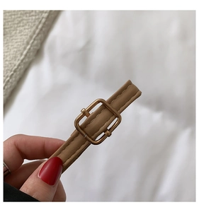 Detail of khaki leather shoulder strap with gold buckle and fine stitching on a shell bag