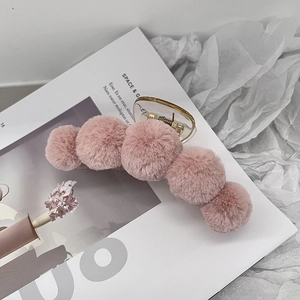 Detail of a large pink plush shark hair claw clip placed on a magazine with soft aesthetics