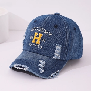 Detailed close-up of distressed denim baseball cap with yellow 3D letter embroidery
