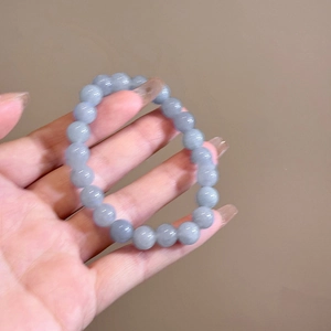 Close-up of light blue-grey agate beaded bracelet held in hand with smooth glossy finish