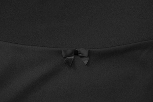 Détail d'une robe noire ajustée avec un nœud décoratif sur une couture incurvée