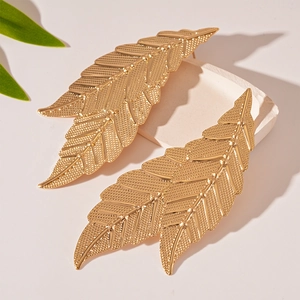 Detailed close-up of golden leaf-shaped earrings featuring fine texture and metallic finish