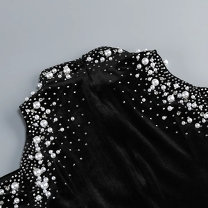 Close-up of black velvet dress neck featuring white pearls and sparkling rhinestone accents